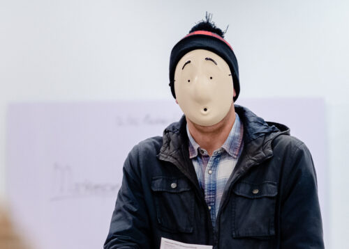 een persoon met een masker op die aan het acteren is