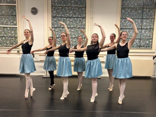 Vrouwen die ballet aan het oefenen zijn, ze hebben zwarte topjes aan en blauwe rokken
