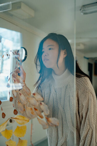 een vrouw die met een loep kijkt naar gedroogde bladeren en bloemen