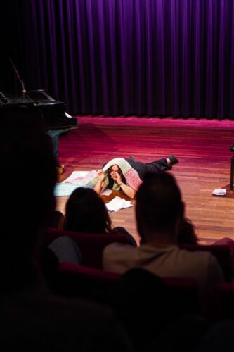 je ziet de vloer van het theater en een artiest ligt op de vloer onder een kleed